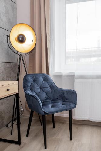 a blue chair next to a lamp and a window at Kamienica Morska Gdynia in Gdynia