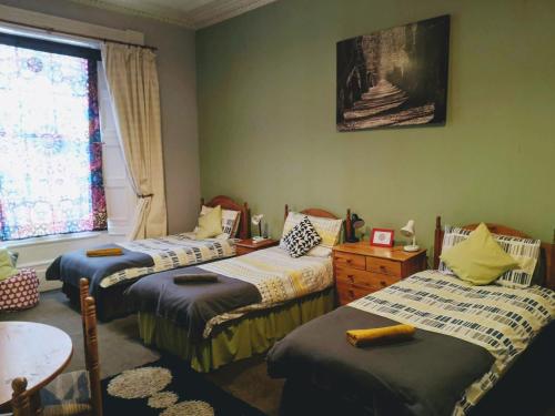 a room with three beds and a table and a window at aabAlree Guest House in Dundee
