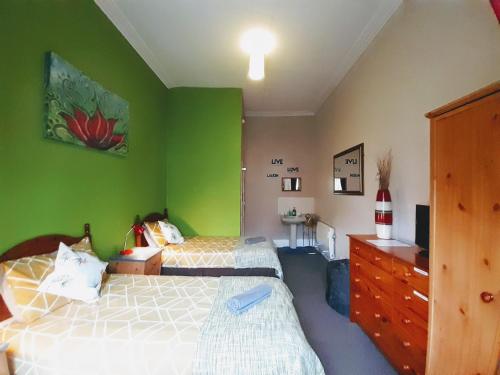 a bedroom with two beds and a green wall at aabAlree Guest House in Dundee