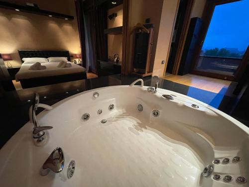 a bathroom with a bath tub with a bed in the background at Attico con vista spettacolare e Jacuzzi in Bologna
