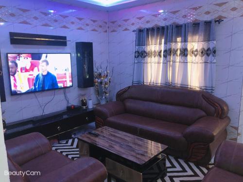 a living room with two couches and a tv at AwaMuuLamin MANNEH GUEST HOUSE in Abuko