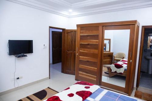 a bedroom with a bed and a tv and a mirror at Mouna in Dakar
