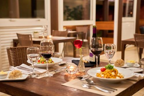 uma mesa com dois pratos de comida e taças de vinho em Hotel Boutique Frangipani em Brotas