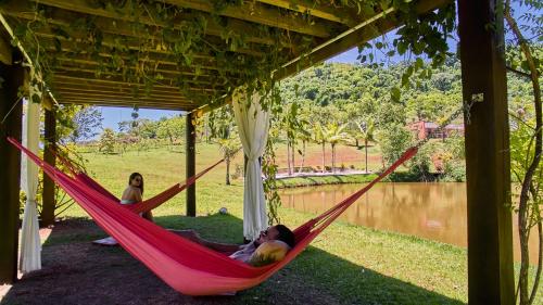 a woman laying in a hammock next to a pond at Hotel Boutique Frangipani in Brotas