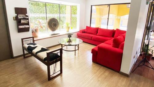 a living room with a red couch and a table at Hotel Aitue in Temuco