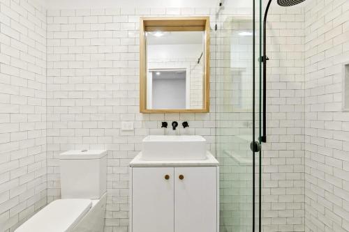 La salle de bains blanche est pourvue d'un lavabo et d'une douche. dans l'établissement Joy Apartment 2, à Lorne