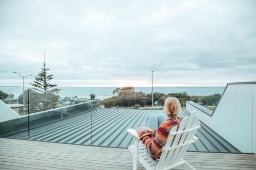 a woman sitting in a white chair on a balcony at Joy Apartment 3 in Lorne