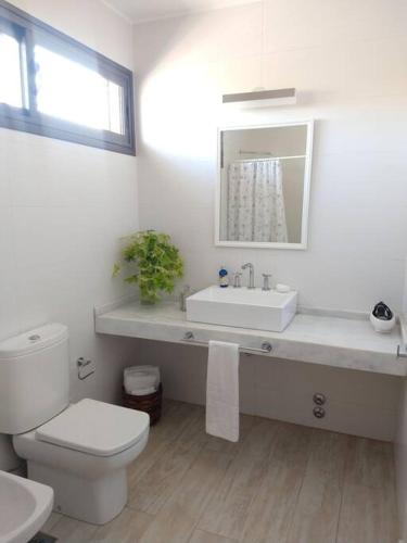a white bathroom with a toilet and a sink at Madame Chacras in Chacras de Coria