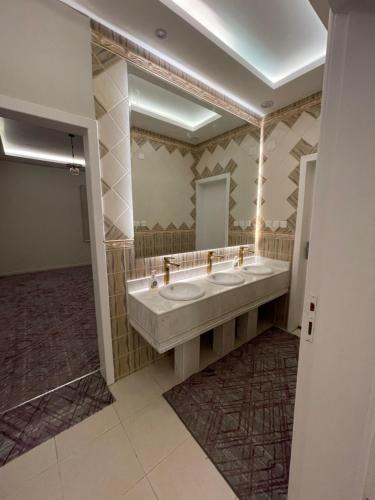een badkamer met 2 wastafels en een grote spiegel bij القمة العالية in Abha