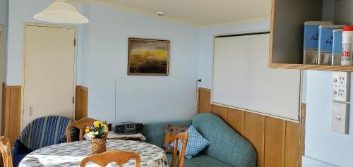 a dining room with a table and a blue couch at Rawhiti Cottage at Kaeppeli's in Kuaotunu