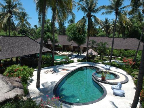 a swimming pool in a resort with palm trees at Trawangan Oasis in Gili Trawangan