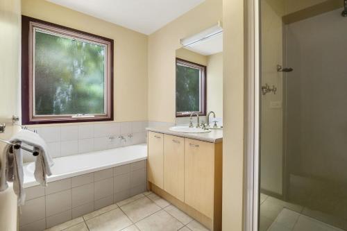 a bathroom with a tub and a sink and a window at Swingbridge in Lorne
