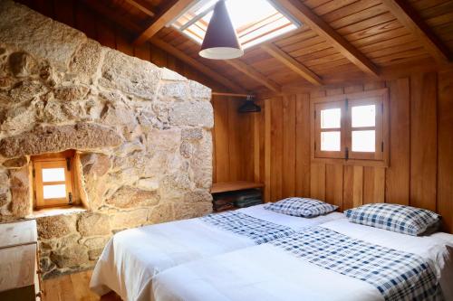 um quarto com uma cama e uma parede de pedra em Comfortable rural cottage in ancient village in the Douro region em Viseu