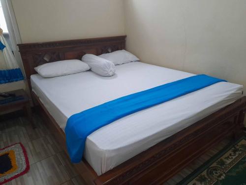a bed with a blue blanket and two pillows on it at Shinta Syariah Homestay Dieng RedPartner in Dieng