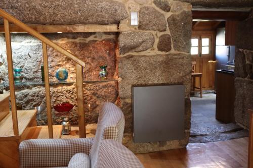 a living room with a stone wall and a chair at Comfortable rural cottage in ancient village in the Douro region in Viseu