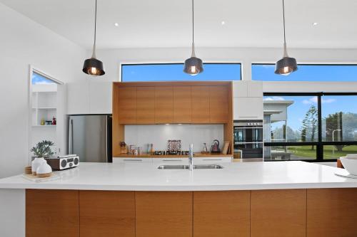 a kitchen with a white counter top and wooden cabinets at Tadasana in Apollo Bay