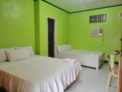 Habitación con 2 camas y pared verde. en M&E Guesthouse en Boracay