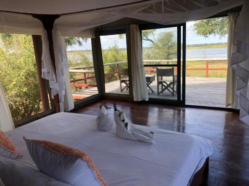 a bedroom with a white bed with a view of the water at Bubezi Camp in Mafuta