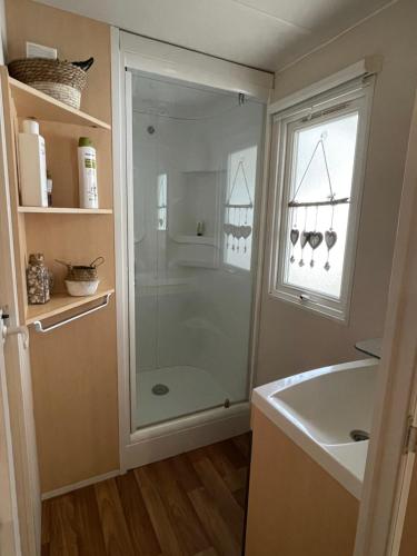 uma casa de banho com um chuveiro, um lavatório e uma janela em mobil home 6 personnes situé à 15 mn d europa park et rulantika em Boofzheim
