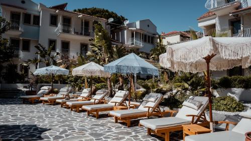 a row of lounge chairs and umbrellas on a patio at Salonika Suites in Oludeniz