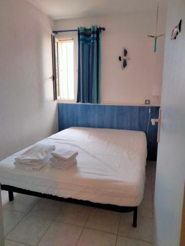 une chambre avec un lit avec des draps blancs et une fenêtre dans l'établissement Joli T2 résidence naturiste ULYSSE, à Leucate