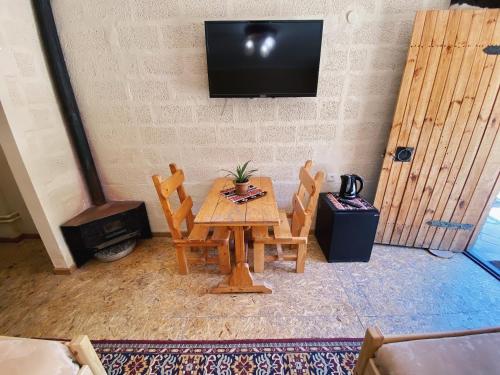 a wooden table with two chairs and a television on a wall at Hovek Guest House in Dilijan