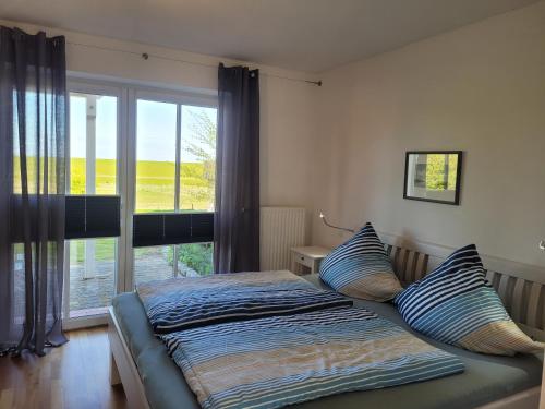 een bed in een slaapkamer met een groot raam bij Ferienhaus Wattenmeerblick in Nordstrand