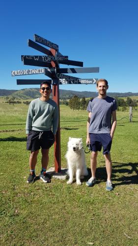 two men standing in front of a sign with a white dog at The Wattle Lodge in Glendon Brook