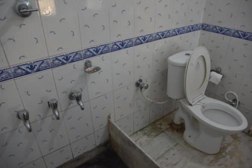 a dirty bathroom with a toilet in a room at Hotel Himshikhar in Chaukori