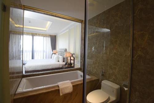 a bathroom with a tub and a bedroom with a bed at Phu Cuong Hotel Ca Mau in Cà Mau