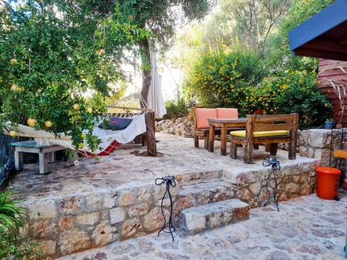 een patio met een tafel en stoelen aan een stenen muur bij Çınarlar Apart Hotel KAŞ in Kas