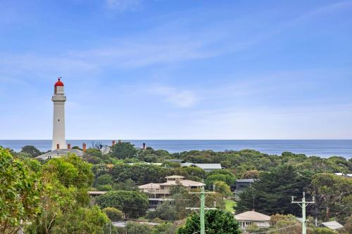 a lighthouse on a hill with the ocean in the background at Aireys Delight in Aireys Inlet