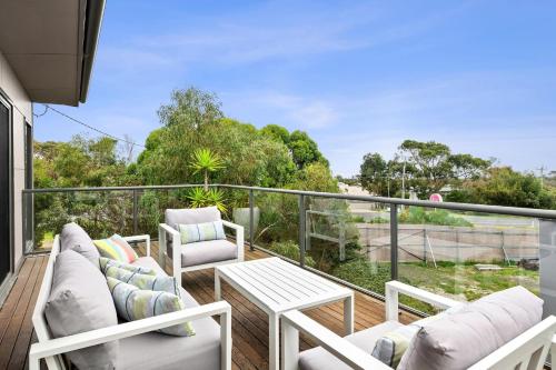 a balcony with white furniture and a view of trees at Aireys Delight in Aireys Inlet