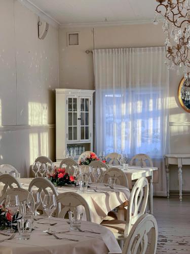 a dining room with white tables and chairs and a chandelier at Hotel Onni in Porvoo