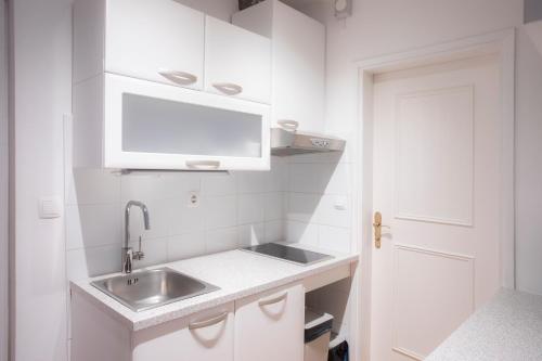 eine kleine weiße Küche mit einem Waschbecken und einer Tür in der Unterkunft Duplex Apartment Panj Kranjska Gora in Kranjska Gora