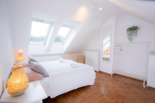 ein weißes Schlafzimmer mit einem weißen Bett und Fenstern in der Unterkunft Duplex Apartment Panj Kranjska Gora in Kranjska Gora