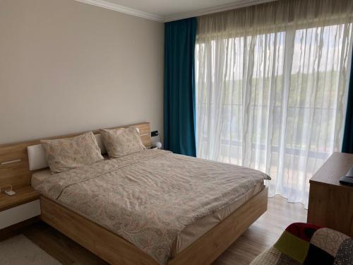 a bedroom with a bed and a large window at D&N Apartments Синеморец in Sinemorets