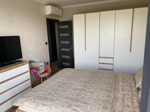 a bedroom with a bed and a tv and a dresser at D&N Apartments Синеморец in Sinemorets