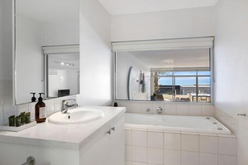 La salle de bains blanche est pourvue d'une baignoire et d'un lavabo. dans l'établissement Apartment 18 Kalimna, à Lorne