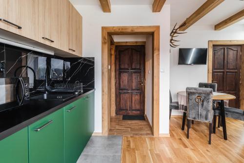a kitchen with green cabinets and a wooden door at Apartamenty Sichlańskie in Murzasichle