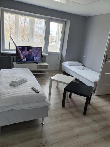 a room with two beds and a flat screen tv at Nakvynė Rokiškyje in Rokiškis