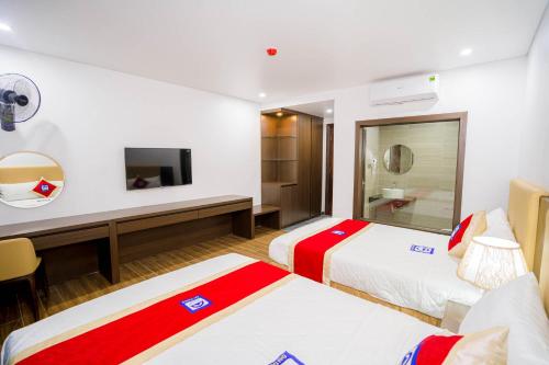a hotel room with two beds and a television at Khách Sạn Đại Dương FLC Sầm Sơn in Sầm Sơn