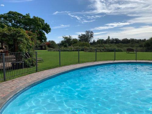 a large blue swimming pool next to a fence at Gerald's Gift Guest House in Addo