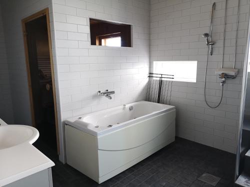 a white bathroom with a tub and a sink at The HOME of Hiisi in Nummela