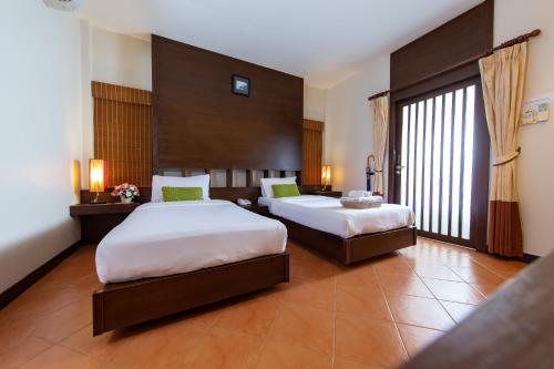 a hotel room with two beds and a large window at The RiverKwai Bridge Resort in Kanchanaburi City
