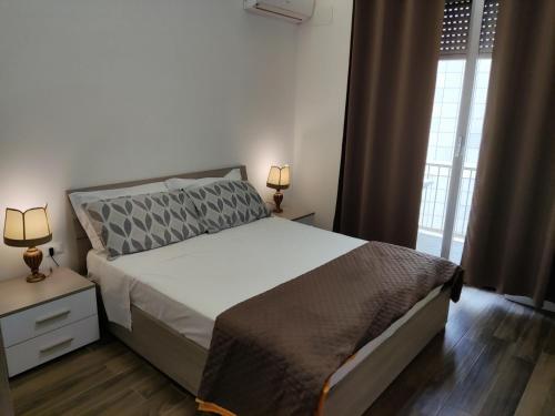 a bedroom with a bed and two lamps and a window at Appartamento Roma Casa Vacanza Sea House Rome 50 metri dal mare in Lido di Ostia
