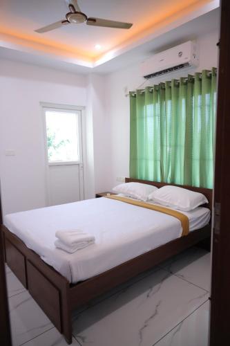 Schlafzimmer mit einem großen Bett und einem grünen Fenster in der Unterkunft Calais7 in Thodupuzha