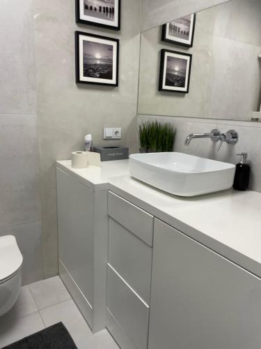 a white bathroom with a sink and a toilet at Centrum 9 in Kołobrzeg