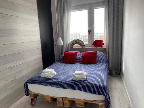 a bedroom with a bed with red pillows and a window at Centrum 9 in Kołobrzeg