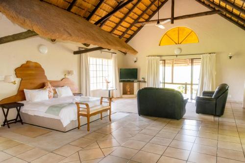 a bedroom with a bed and a living room at Lions Rock Rapids - Lodge in Hazyview